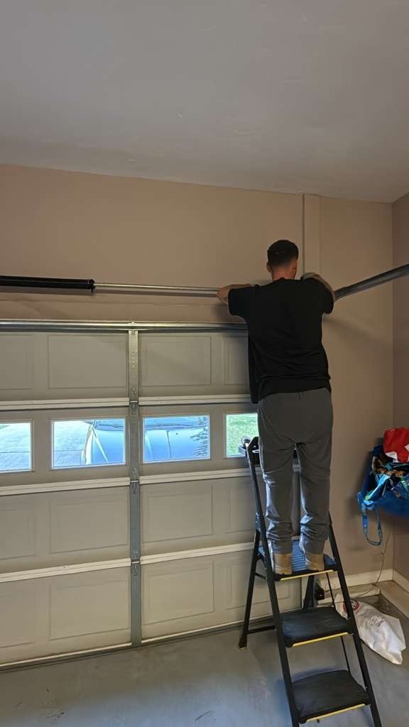 Technician on a stepladder reaching the top panel of a door with small window panels