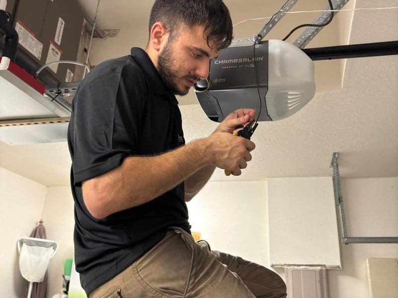 Technician with a wire tool working on a ceiling-mounted garage door opener