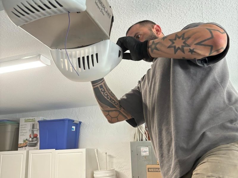 Technician in work gloves working on a ceiling-mounted garage door opener